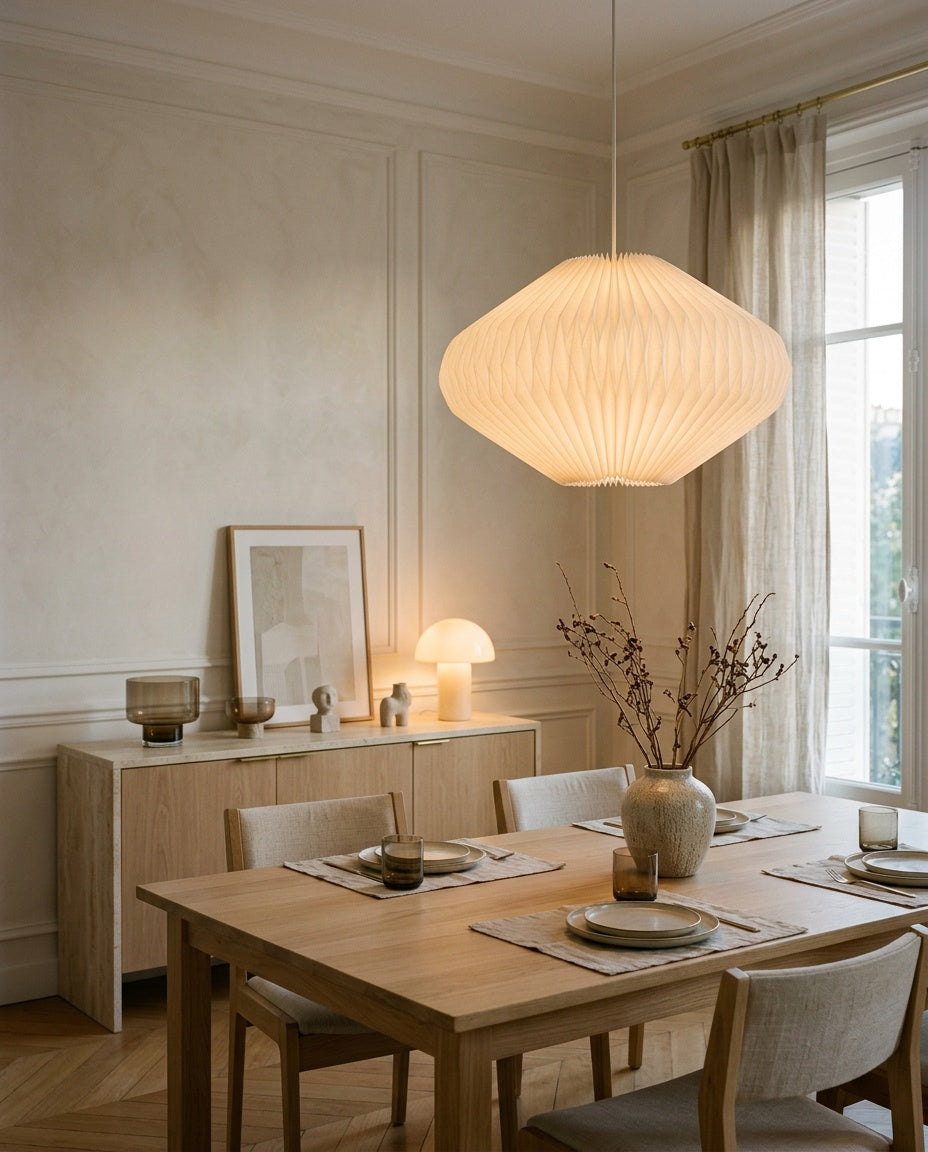 Pleated paper pendant light glowing above an oak table
